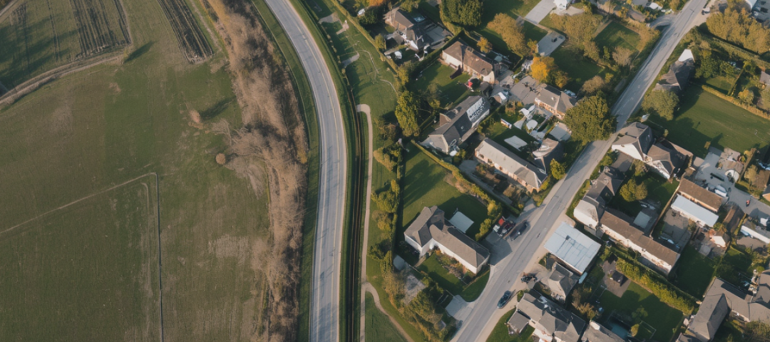 Aerial of a growing suburban edge — where farmland meets new rooftops. This is visually specific to the region and captures the literal growth pressure the post is about.